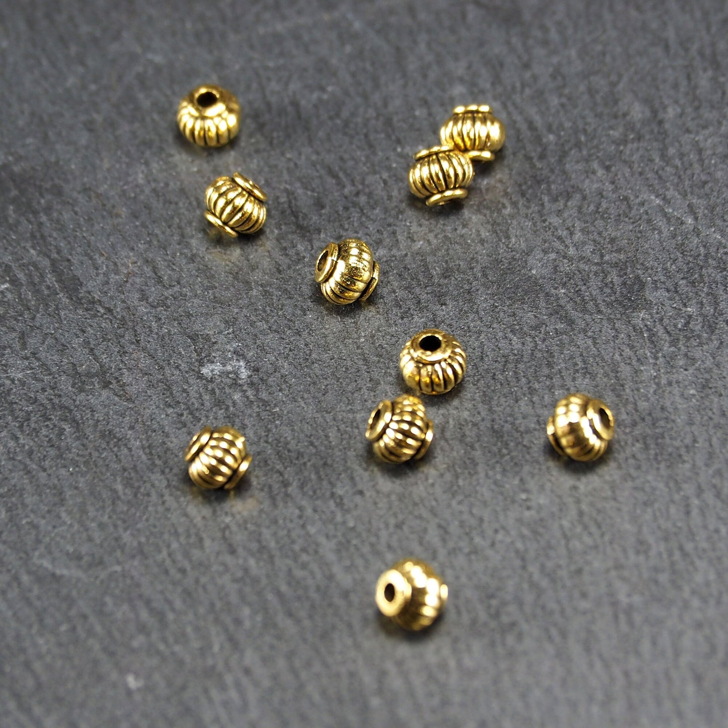 10 kleine Perlen 4mm, geriffelt, Barrel, antik goldfarben, 10469